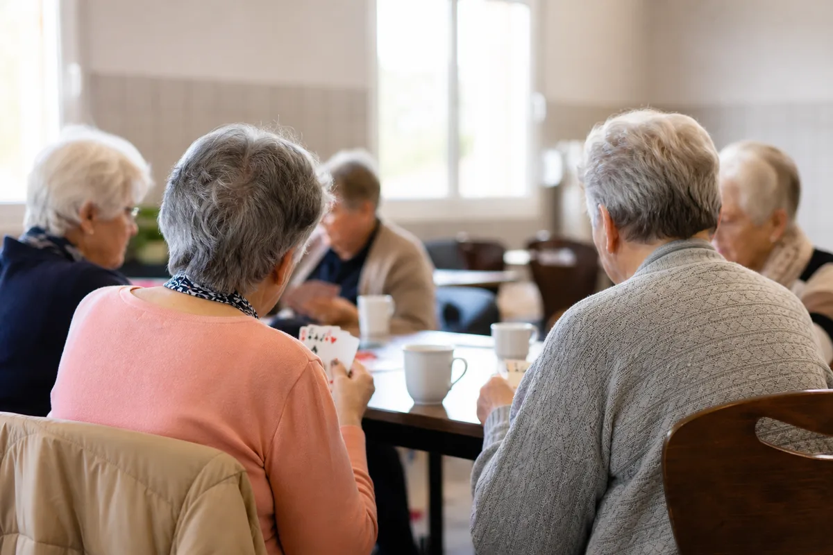 Groupe de personnes âgées partageant un café autour d&rsquo;une table dans une salle associative